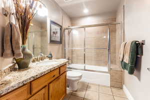 Full bathroom featuring tile patterned flooring, vanity, toilet, and enclosed tub / shower combo