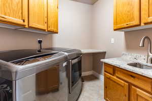 Laundry area featuring cabinets, light tile patterned floors, washer and dryer, and sink