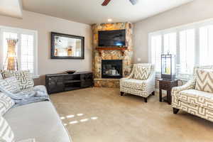 Living room with a fireplace, light colored carpet, and ceiling fan