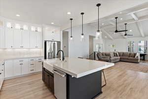 Kitchen with white cabinetry, sink, stainless steel appliances, an island with sink, and decorative backsplash