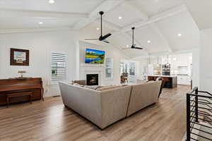 Living room with light wood-type flooring, lofted ceiling with beams, and ceiling fan