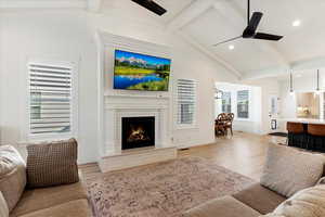 Living room featuring ceiling fan, lofted ceiling with beams, and light wood-type flooring