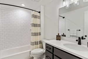 Full bathroom with vanity, shower / bath combination with curtain, and toilet