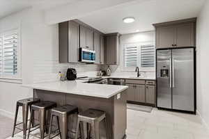 Kitchen with a breakfast bar, sink, decorative backsplash, kitchen peninsula, and stainless steel appliances