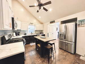 Kitchen with sink, a center island, high vaulted ceiling, backsplash, and appliances with stainless steel finishes