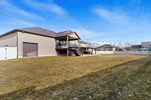 Rear view of property featuring a lawn and a deck with mountain view