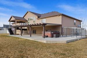 Back of house featuring a hot tub, a patio area, and a lawn