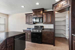 Kitchen with black appliances, dark brown cabinets, a textured ceiling, and light hardwood / wood-style flooring