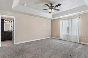 Spare room with light colored carpet, a raised ceiling, and ceiling fan