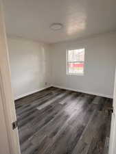 Empty room with crown molding and dark hardwood / wood-style flooring