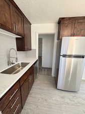 Kitchen featuring appliances with stainless steel finishes, backsplash, a textured ceiling, dark brown cabinetry, and sink