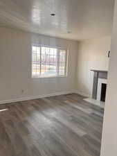 Unfurnished living room featuring dark hardwood / wood-style flooring and a textured ceiling