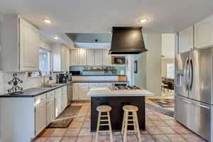 Kitchen featuring white cabinetry, sink, stainless steel appliances, a kitchen island, and light tile patterned flooring