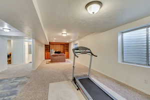 Exercise area featuring a textured ceiling and light carpet