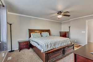 Bedroom with light carpet, ceiling fan, and ornamental molding