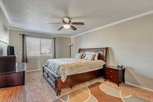 Bedroom featuring light carpet, a textured ceiling, ceiling fan, and crown molding