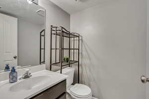 Bathroom with vanity, a textured ceiling, and toilet