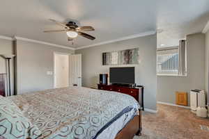 Bedroom featuring ceiling fan, light colored carpet, and ornamental molding