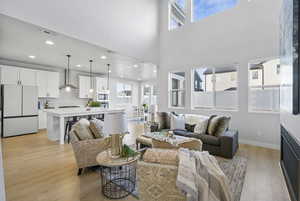 Living room with a wealth of natural light, a towering ceiling, and light hardwood / wood-style floors