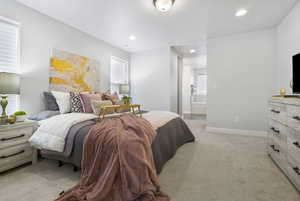 Bedroom with ensuite bath and light colored carpet