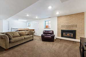 Living room featuring a fireplace, carpet, and a textured ceiling