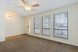 Carpeted spare room featuring ceiling fan and a healthy amount of sunlight