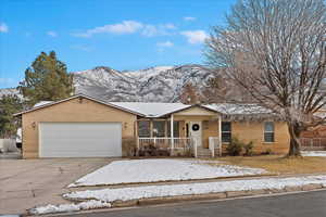 Ranch-style home featuring covered porch, a mountain view, and a garage