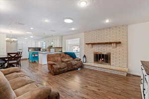 Living room featuring a fireplace, a textured ceiling, hardwood / wood-style flooring, and a notable chandelier