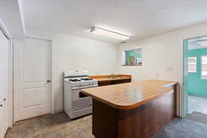 Kitchen with a textured ceiling, white gas stove, and sink