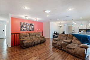 Living room with a textured ceiling, dark hardwood / wood-style flooring, and an inviting chandelier