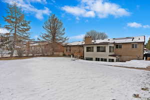 Snow covered rear of property with solar panels