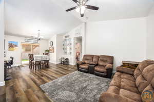 Living room featuring ceiling fan with notable chandelier, dark hardwood / wood-style flooring, and lofted ceiling