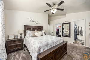 Carpeted bedroom featuring a spacious closet, a closet, lofted ceiling, and ceiling fan