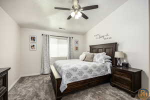 Carpeted bedroom with ceiling fan and vaulted ceiling