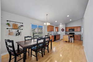 Dining area featuring sink, a chandelier, vaulted ceiling, and light wood-type flooring