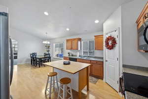 Kitchen featuring a center island, an inviting chandelier, a kitchen breakfast bar, sink, and light hardwood / wood-style floors