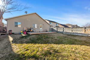 Rear view of property with a deck and a lawn