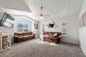 Living room featuring a textured ceiling, ceiling fan, lofted ceiling, and carpet floors