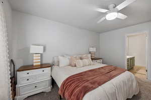 Bedroom with ceiling fan, light tile patterned floors, and connected bathroom