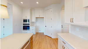 Kitchen with light stone countertops, appliances with stainless steel finishes, tasteful backsplash, and white cabinetry