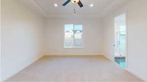 Carpeted spare room with ceiling fan and a tray ceiling