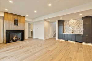 Unfurnished living room with a fireplace, sink, and light wood-type flooring