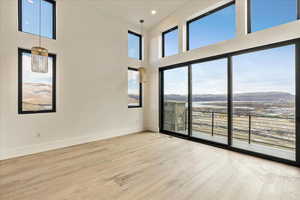 Empty room featuring a mountain view, wood-type flooring, a wealth of natural light, and a towering ceiling