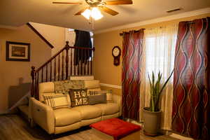 Living room featuring ceiling fan, wood-type flooring, and crown molding