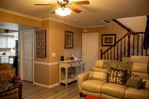 Living room with ceiling fan, hardwood / wood-style floors, and ornamental molding