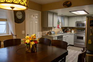 Kitchen featuring white cabinets, sink, decorative backsplash, light wood-type flooring, and stainless steel appliances