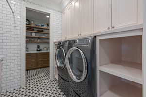 Washroom featuring cabinets, crown molding, and washing machine and clothes dryer