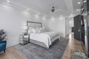 Bedroom with hardwood / wood-style floors, a raised ceiling, and ceiling fan