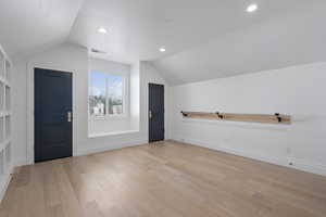 Additional living space featuring built in features, light hardwood / wood-style flooring, and lofted ceiling