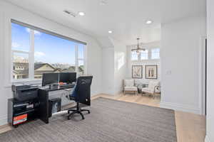 Office space with a chandelier, light wood-type flooring, and a wealth of natural light